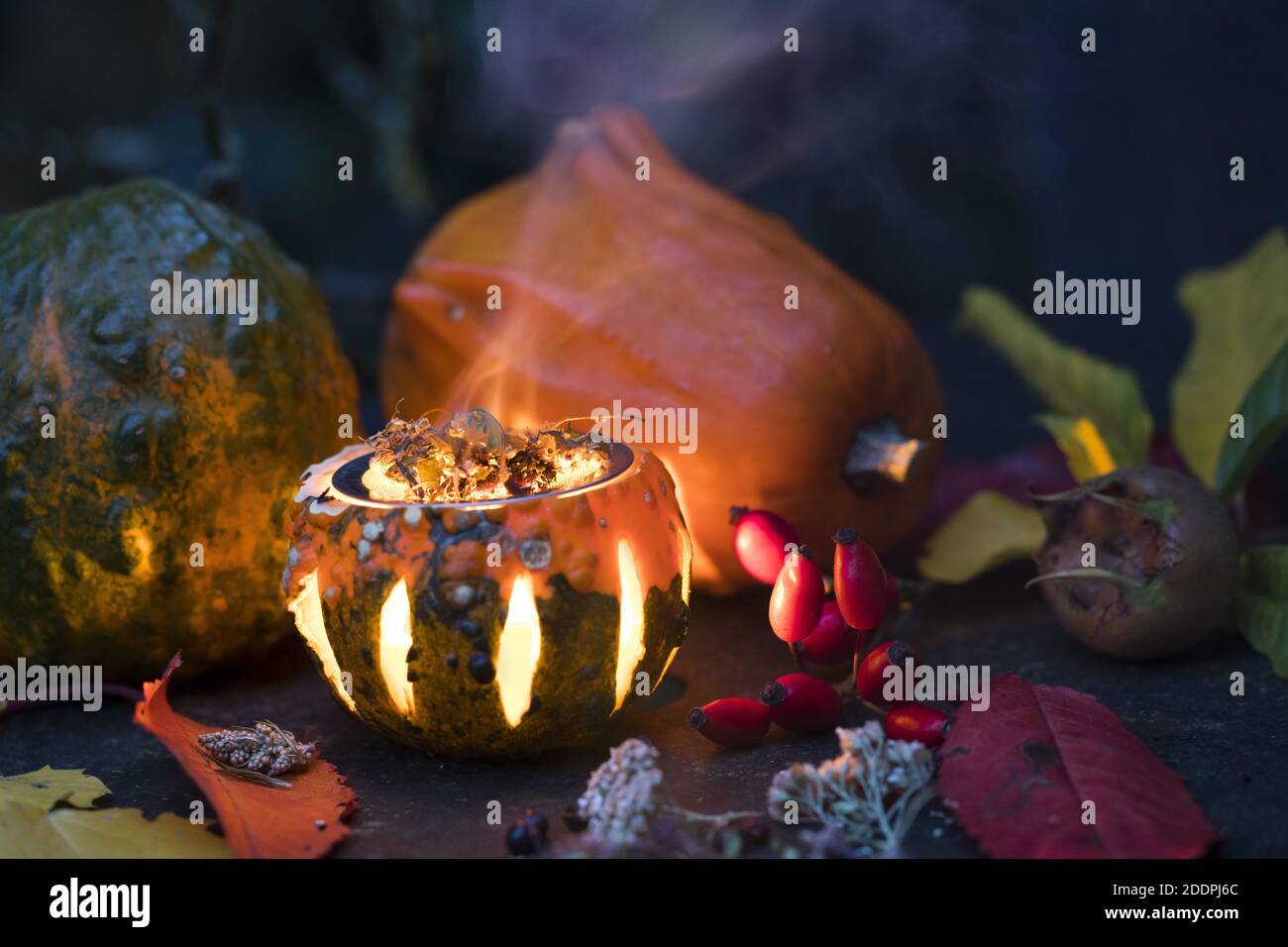 Rauchen mit aromatischen Kräutern in einem Kürbis mit Teelicht, Deutschland Stockfoto