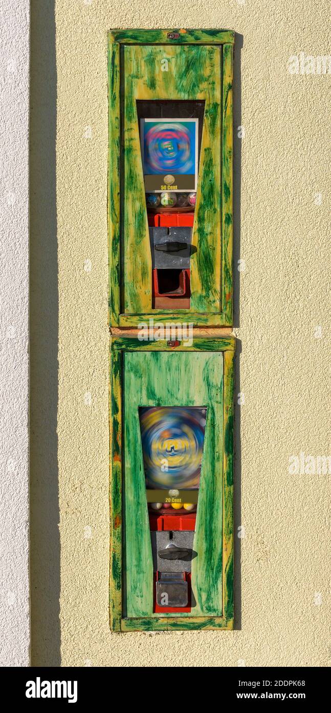Zwei Gummiballmaschinen in alten Metallkisten in einem Wand Stockfoto