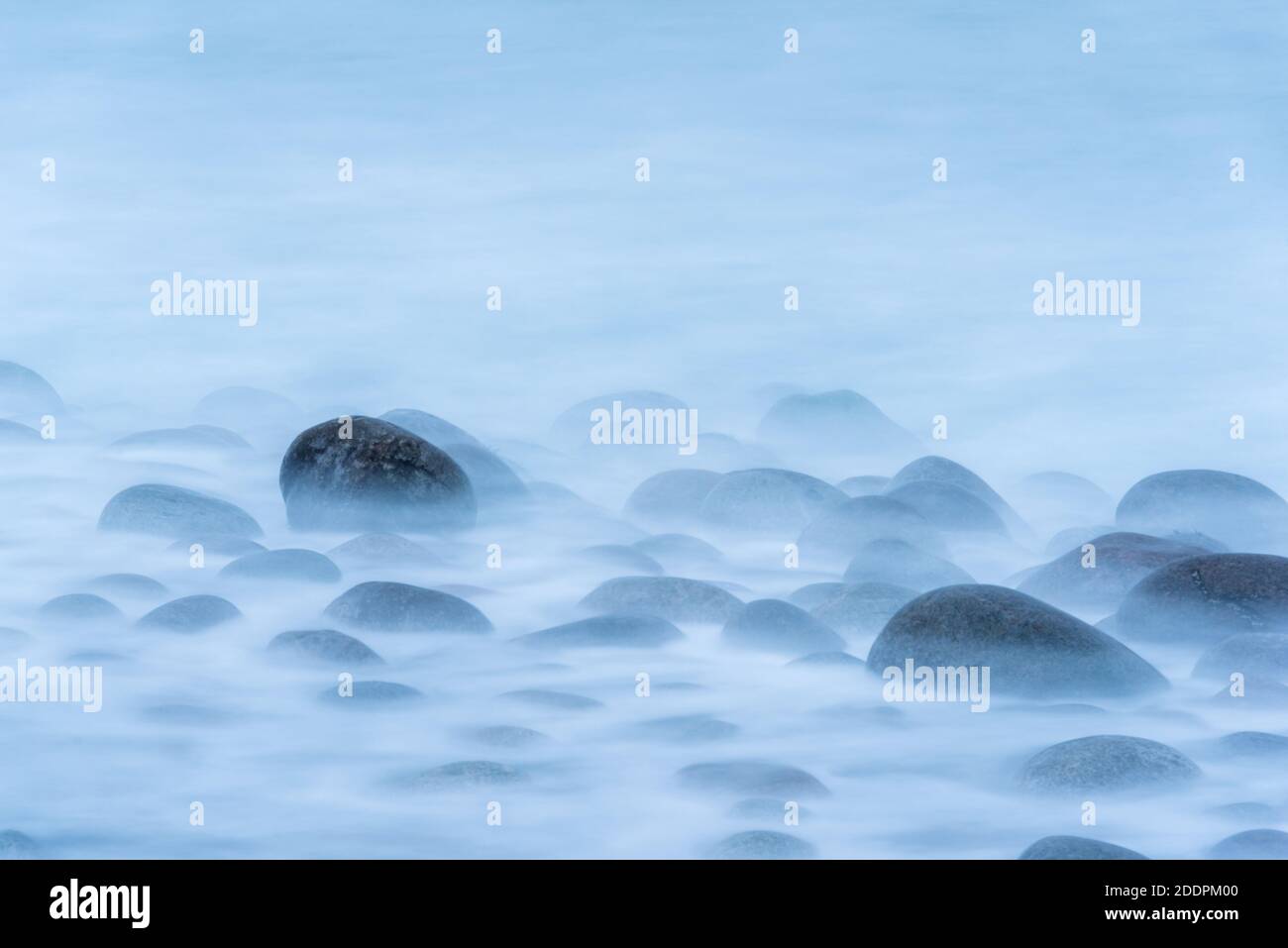 Lange Exposition von Wellen krachen auf großen runden Felsbrocken auf Shore erzeugt einen Nebel wie Schaum Stockfoto