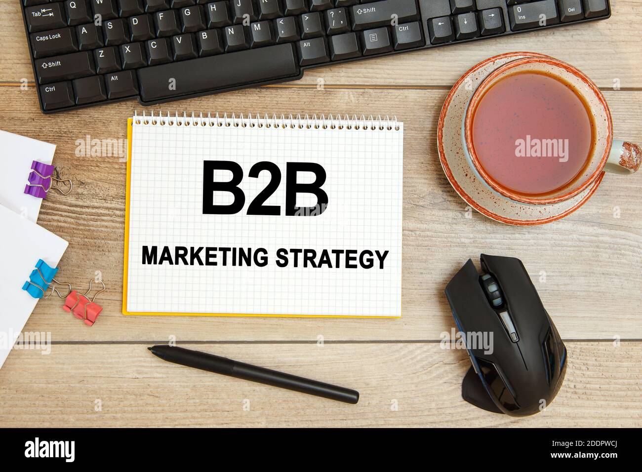 Schreibtisch und Notebook mit Text - B2B Marketing Strategie, Tastatur und einer Tasse Tee Stockfoto