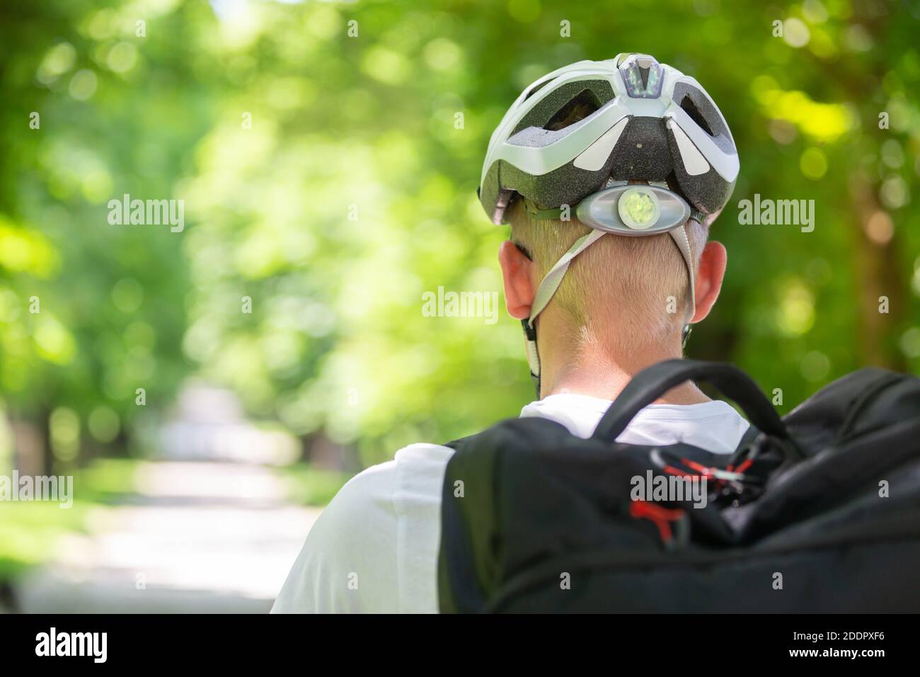 Rückansicht des nicht erkennbaren Mannes, der Schutzhelm auf dem Fahrrad trägt Radfahren im Stadtpark Stockfoto