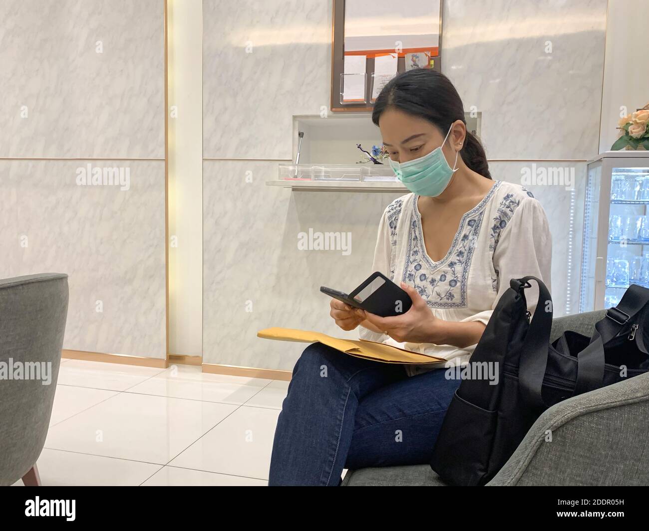Frau in Schutzmaske mit Smartphone Stockfoto