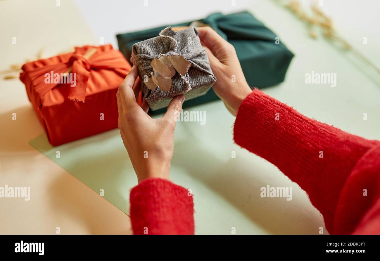 Junge Frau hält ein Zero Waste Geschenk in traditionellen japanischen Furoshiki-Stil verpackt. Weihnachtsdekorationen, mittlere Nahaufnahme Stockfoto