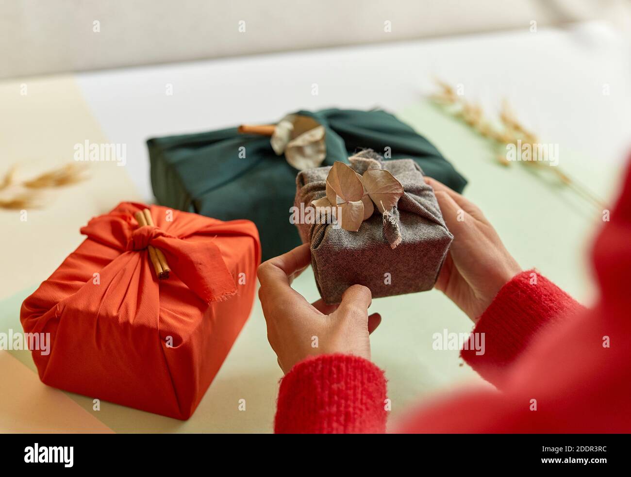 Weibliche Hände halten ein Geschenk in braunem Stoff, Minimalismus Konzept, 4k Stockfoto