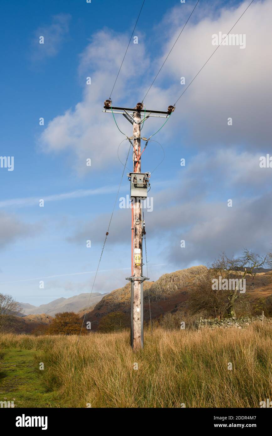 Ein am Mast montierter Abschalttransformator am Ende eines Durchlaufs von 11kv 3-Phasen-Überkopfkabeln in einem ländlichen Raum in Cumbria. Stockfoto