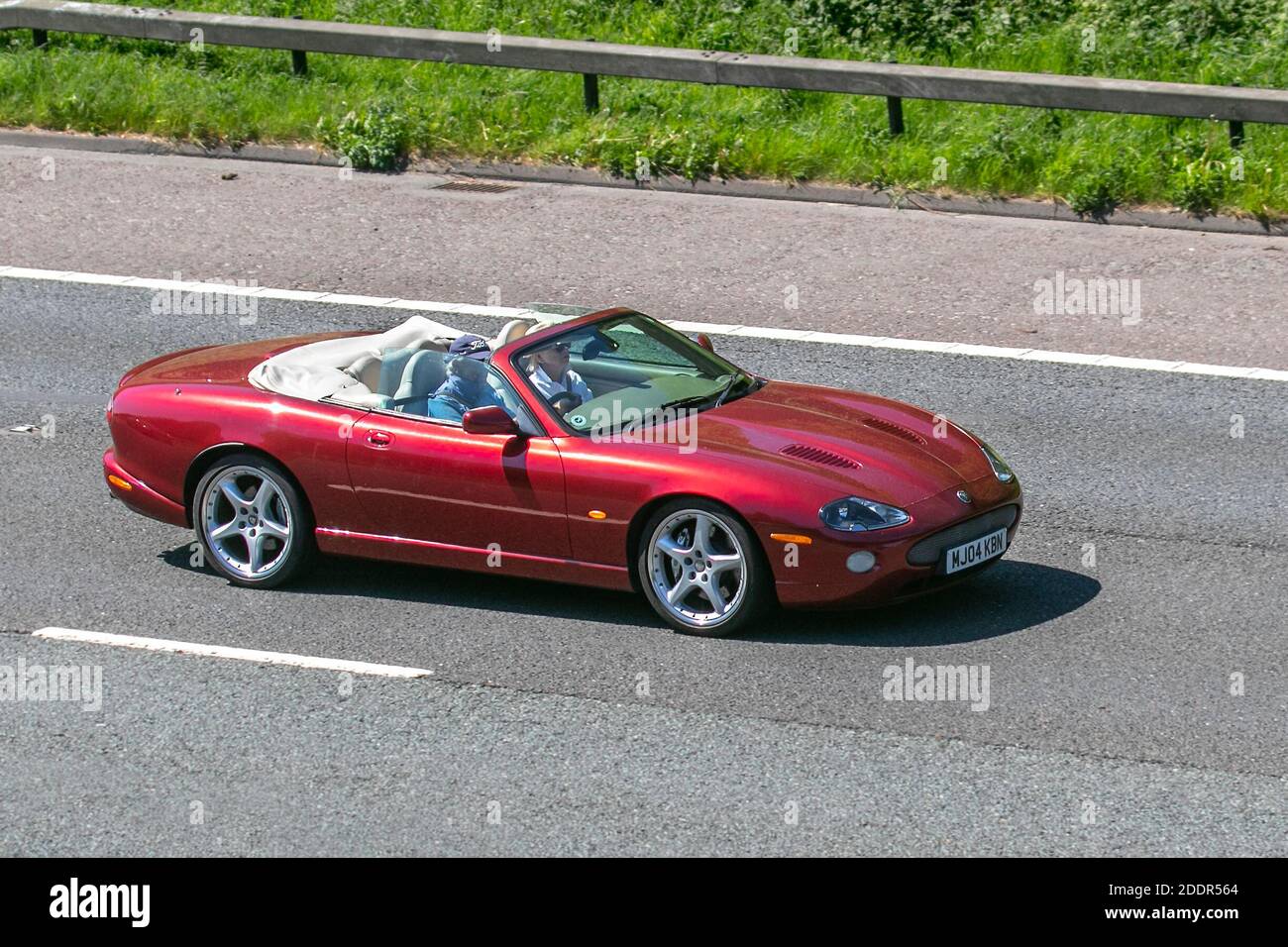 2004 Red Jaguar XKR Cabrio Auto; Fahrzeugverkehr, bewegliche Fahrzeuge, Autos, Fahrzeug fahren auf britischen Straßen, Motoren, Fahren auf der Autobahn M6 Autobahn britischen Straßennetz. Stockfoto