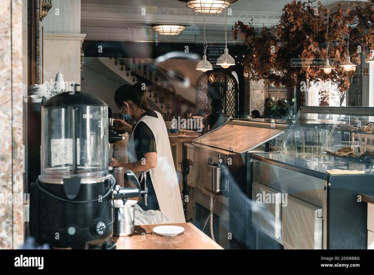 Madrid, Spanien - 11. Oktober 2020: Blick durch das Fenster eines Cafés mit Vintage-Dekoration und einer Kellnerin, die Kaffee zubereitet. Stockfoto