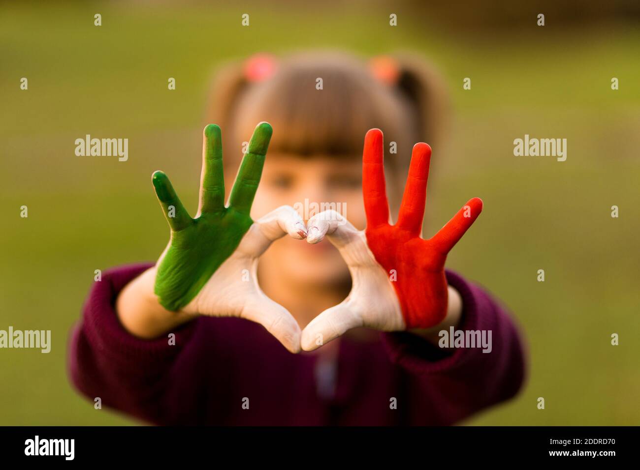 Herz Form von Kindern handbemalt in italien Flagge Farben, Kinder Körpersprache, Kinder Liebe Konzept. Herz Hand auf Natur Sonnenuntergang Bokeh Hintergrund Stockfoto