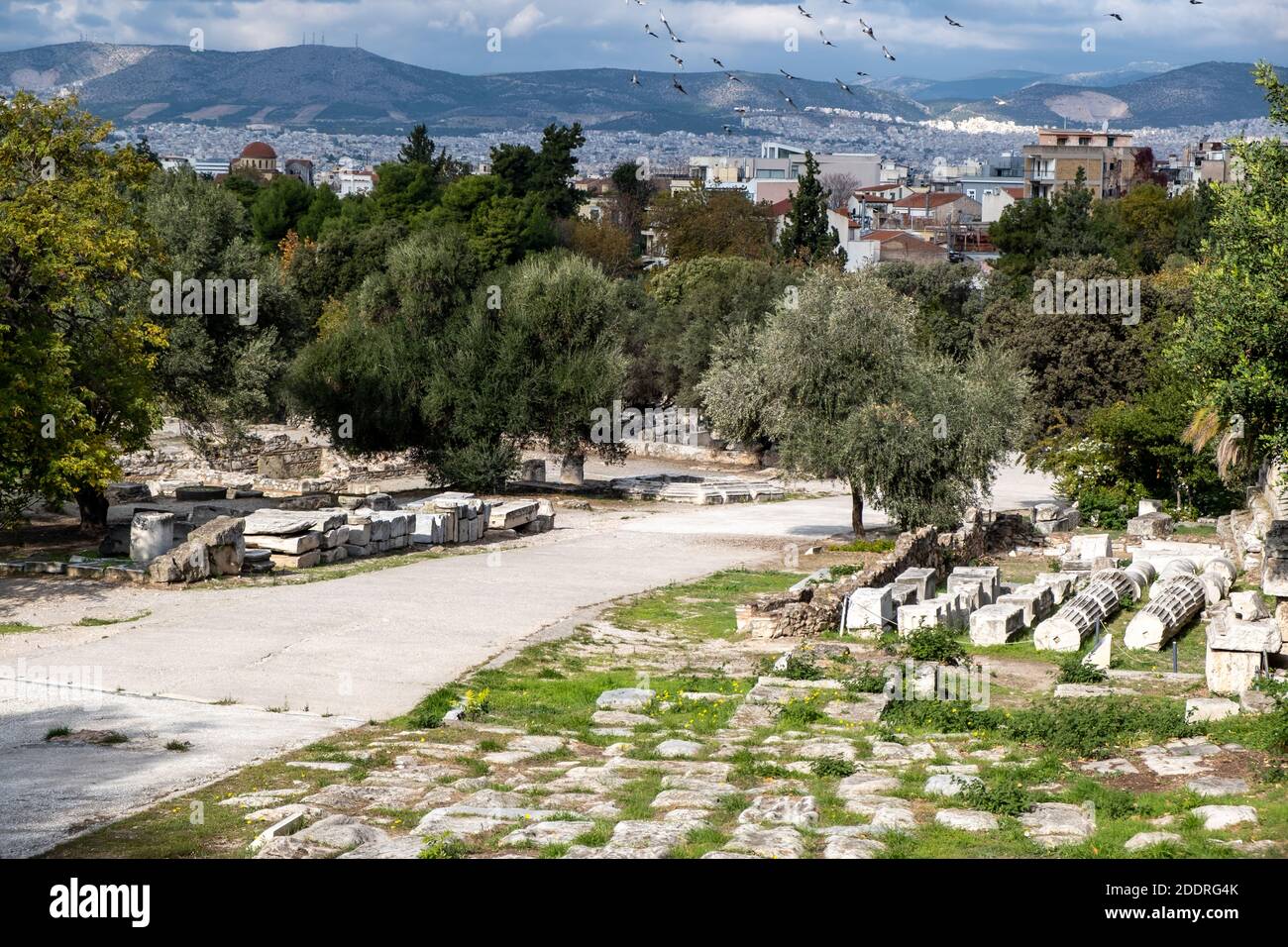 Athen Griechenland, römische Agora. Alte Ruinen, Marmorsäulen auf dem Boden gestapelt, Athen Stadtbild und bewölkten Himmel Hintergrund Stockfoto