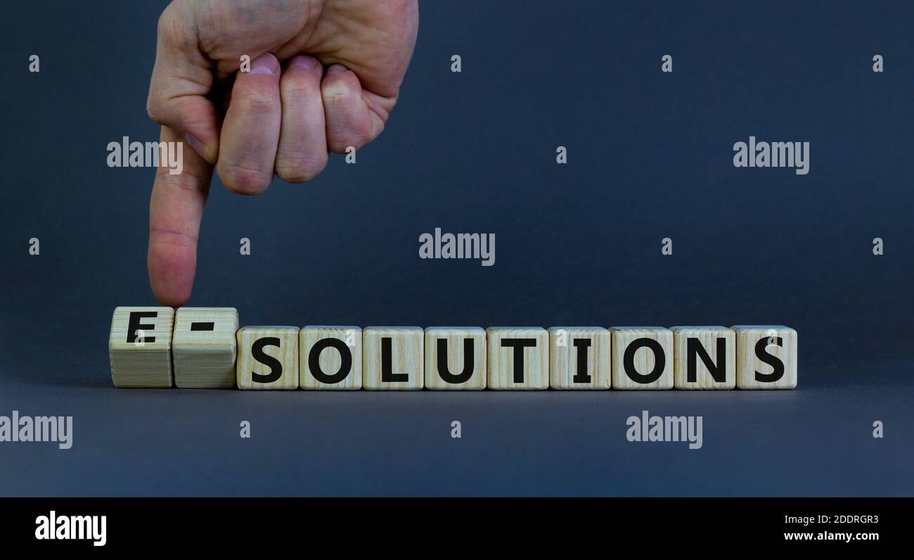 Zeit für e-Lösungen. Männliche Hand falzt Holzwürfel und ändert das Wort "Lösungen" in "e-Lösungen". Schöner grauer Hintergrund, Kopierbereich. Unternehmen A Stockfoto