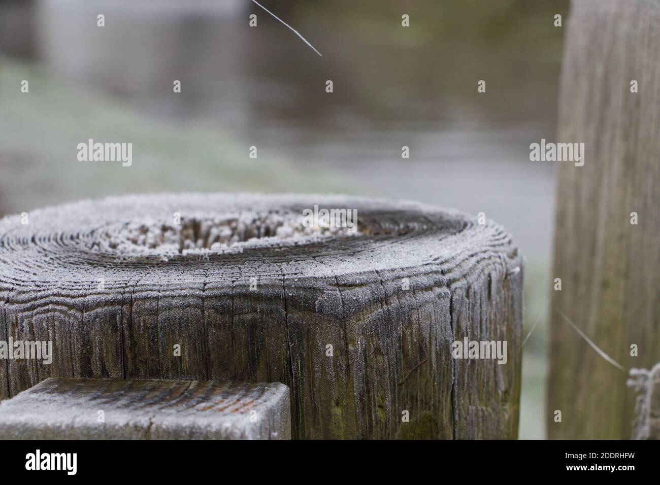 Alte, runde Holzpfosten auf dem Schleppturm. Winterliche Szene auf einem Bauernhof an einem eisigen Morgen. Ruhig und friedlich. Stockfoto