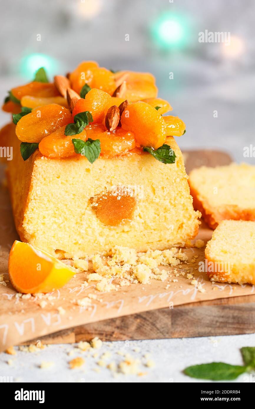 Orange Pound Cake mit frisch gepresstem Orangensaft und Orangenschale, dekoriert mit getrockneten Aprikosen, Minzblättern und Mandeln. Stockfoto