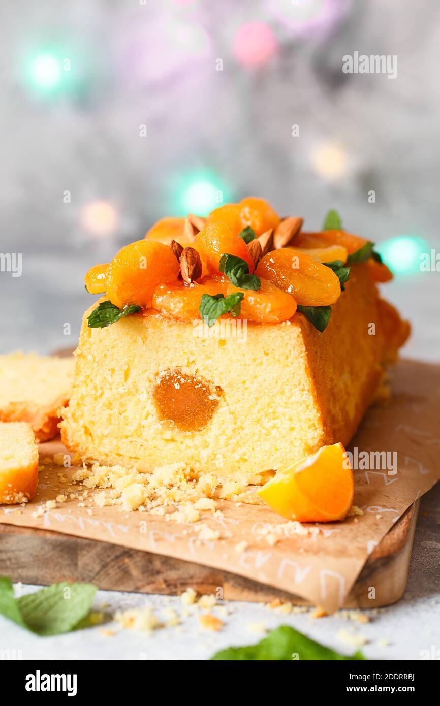Orange Pound Cake mit frisch gepresstem Orangensaft und Orangenschale, dekoriert mit getrockneten Aprikosen, Minzblättern und Mandeln. Stockfoto