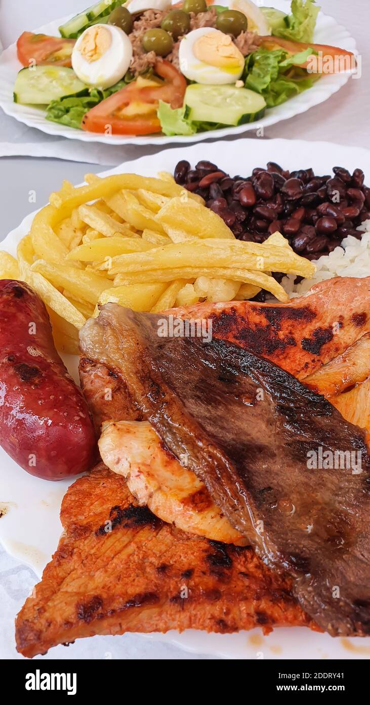 Nahaufnahme von gemischten gegrillten Steaks auf einem Teller, mit Schweinefleisch, Rindfleisch, Huhn und Kartoffeln, selektiver Fokus, vertikal Stockfoto