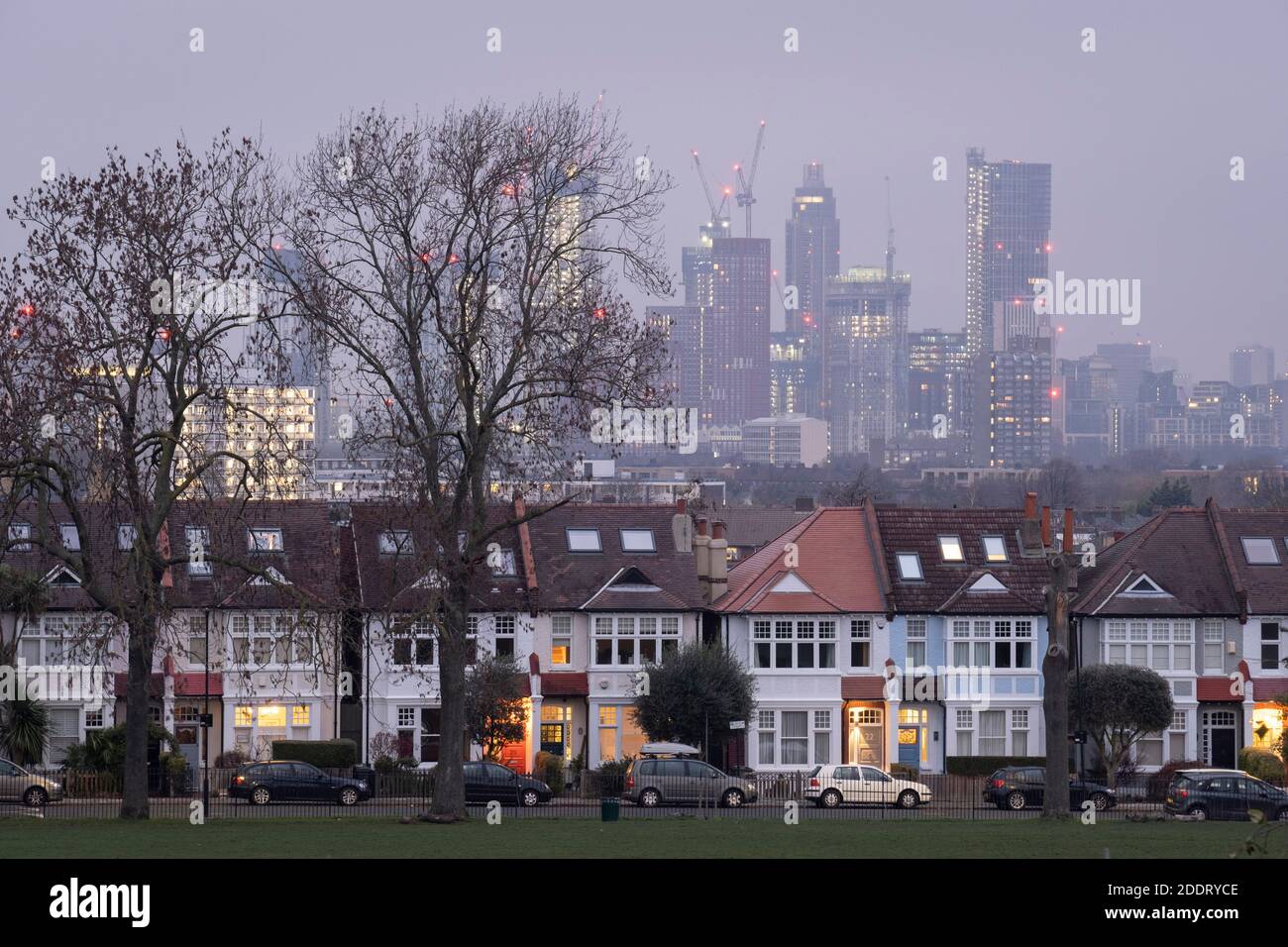 Durch eine Lücke von 100 Jahre alten Eschen, Edwardian Periode Häuser grenzt Ruskin Park in Süd-London mit Wohnhochhäusern in der entfernten Nine Elms Entwicklung in Battersea, am 25. November 2020, in London, England. Stockfoto