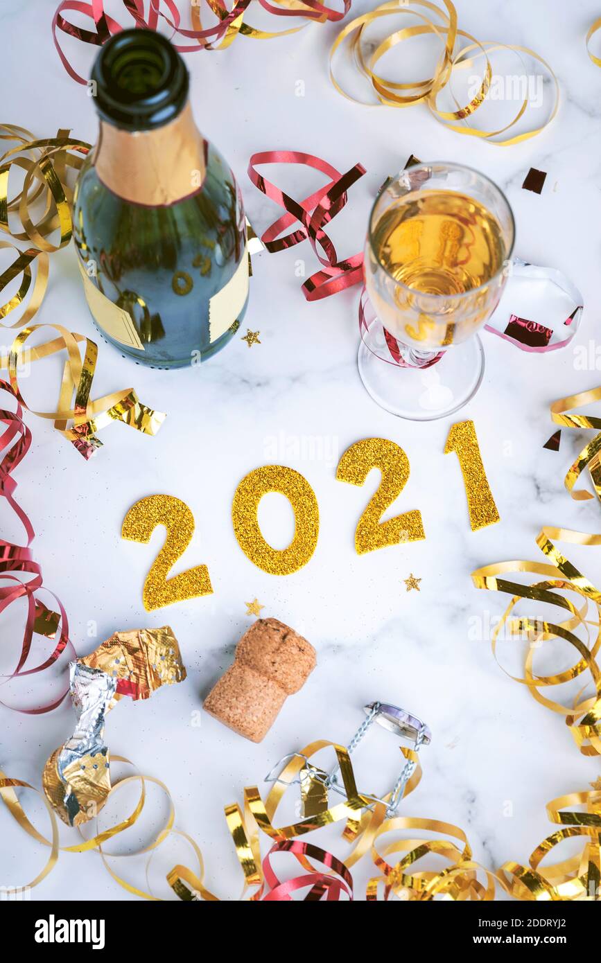 Frohes neues Jahr 2021. Silvester Feier Konzept Hintergrund.Champagner-Flasche mit Glas und Konfetti auf Marmortisch.Selektive Fokus Stockfoto