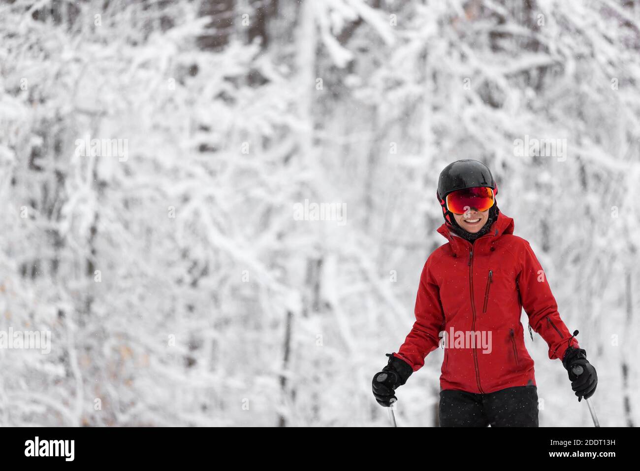 Wintersport glücklich Skifahrer Alpine Skifahren gehen dowhill gegen schneebedeckten Bäumen Hintergrund während Winter Schneesturm. Frau in roter Jacke und Brille Stockfoto