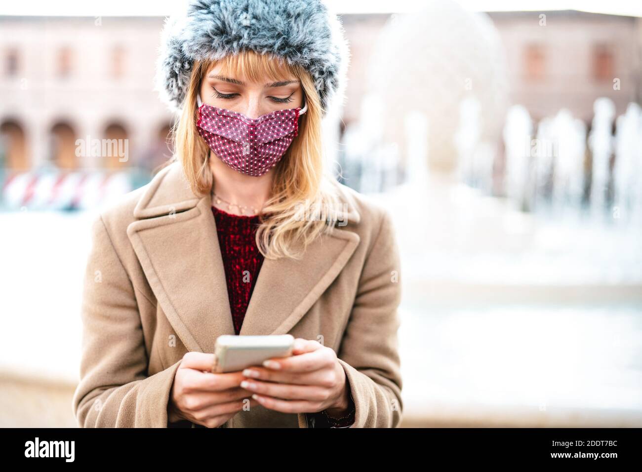Addicted Frau mit Schutzmasken mit Tracking-App auf Handy Smartphone - Junge besorgt Millennial-Sharing-Inhalte auf Social Media Stockfoto