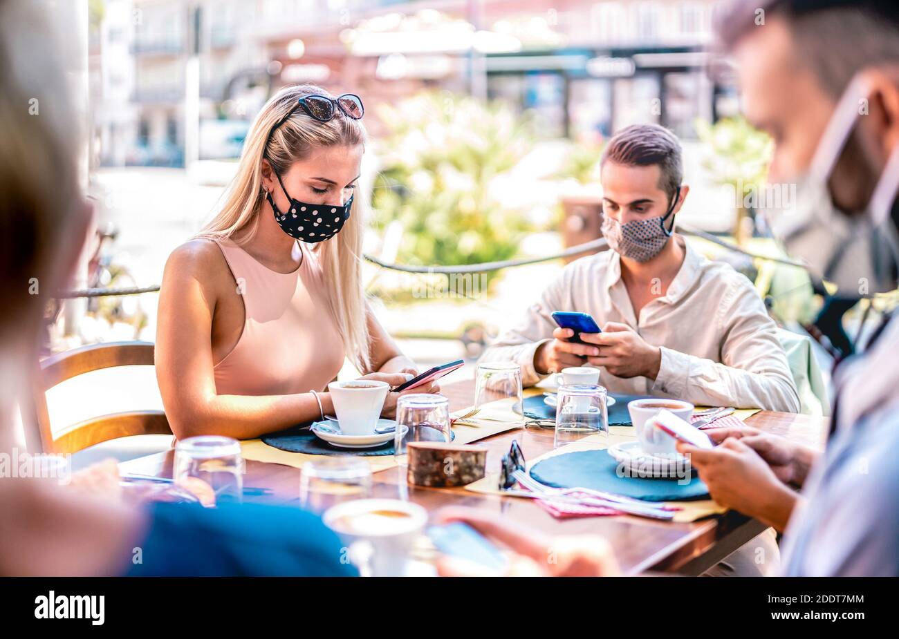 Junge Freunde nutzen mobile Smartphones an der Kaffeebar - Neue normale Lifestyle-Konzept mit Menschen tragen Gesichtsmaske und App zur Kontaktverfolgung wird überprüft Stockfoto