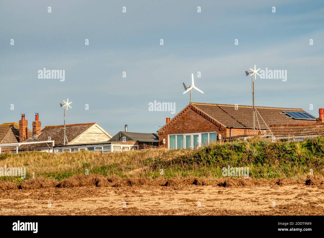 Kleine inländische Mikro-Windturbinen auf Chalets hinter dem Strand bei Snettisham am Ostufer der Wash, Norfolk. Stockfoto