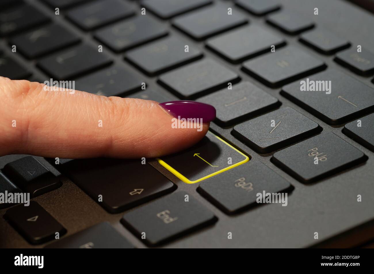 Nahaufnahme des weiblichen Fingers durch Drücken der ENTER-Taste auf der Laptop-Tastatur. Stockfoto