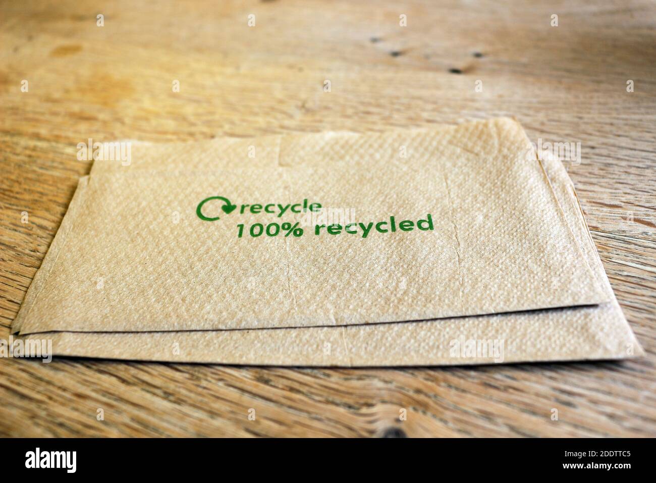 Eine Papierserviette mit den Worten 100% recycelt auf einem Holztisch Stockfoto