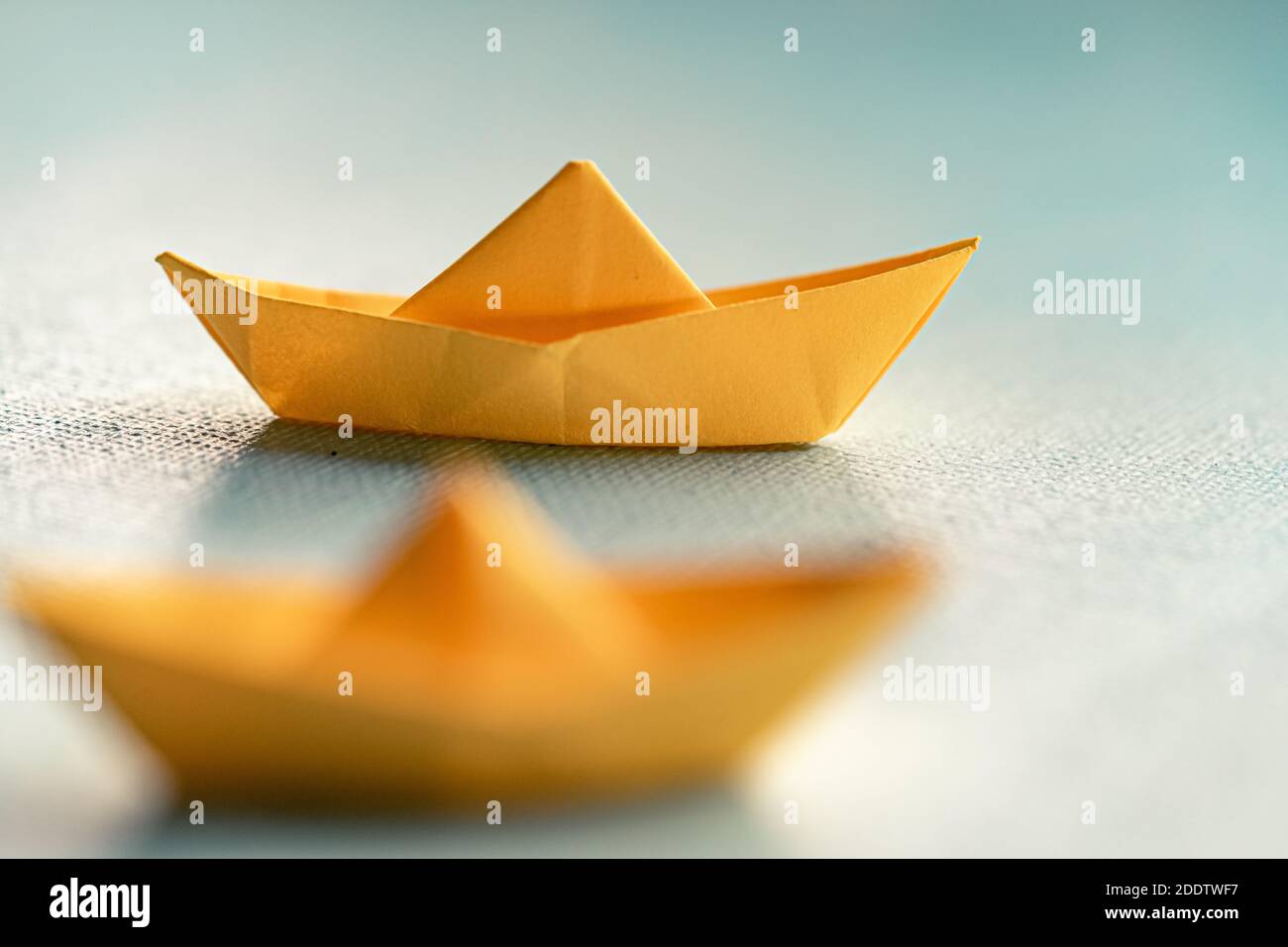 Origami gelbes Segelboot auf einem Meer mit blauem Papier. Papierkunst-Stil Hintergrund mit Schiff und Meer Stockfoto