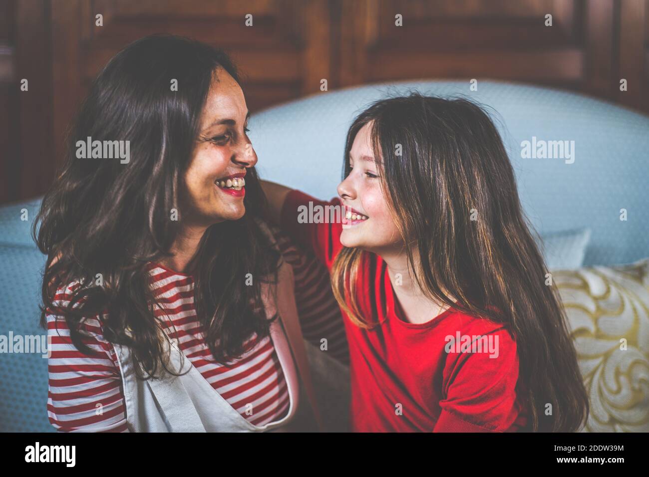 Portrait von Mutter und Tochter lachen und sitzen zusammen Auf dem Sofa - Digitales Porträt der Familie Stockfoto