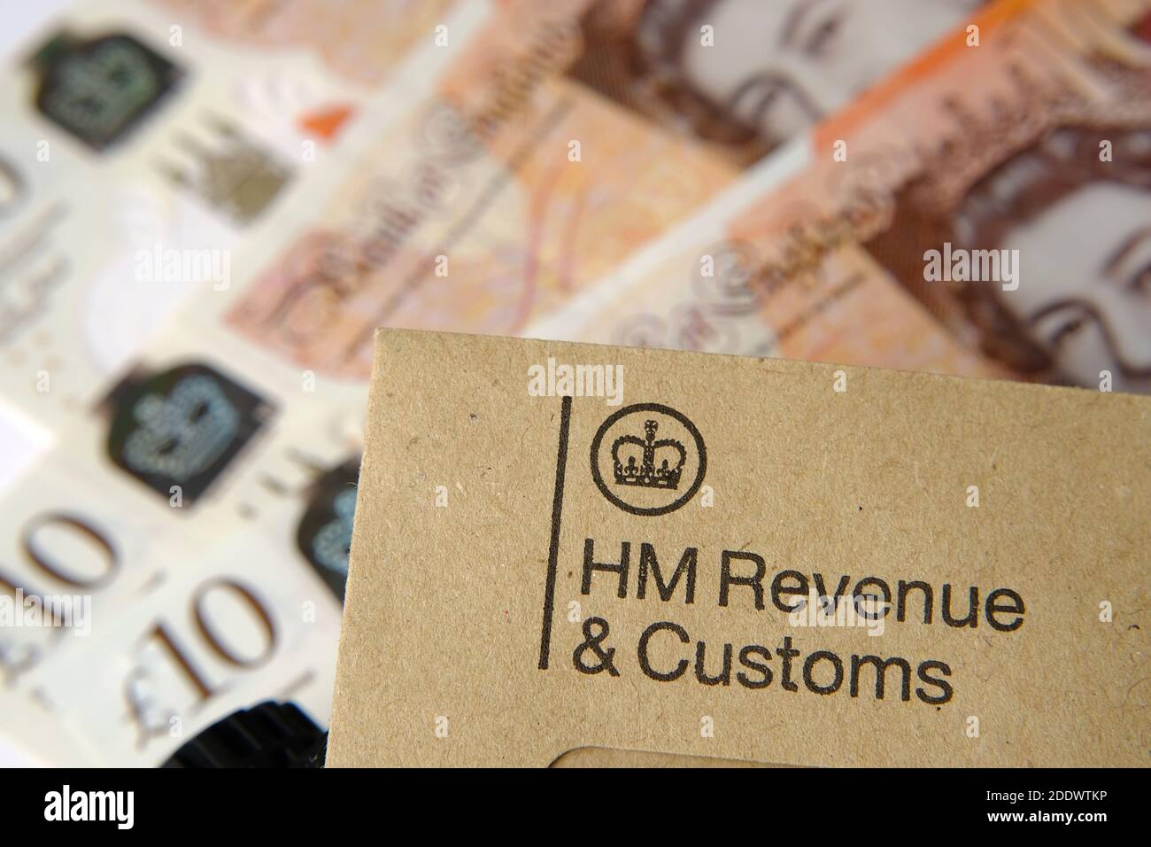 HM Revenue and Customs (HMRC) Brief mit Logos mit dem braunen Umschlag und verschwommenem Geld auf der Rückseite. Stockfoto
