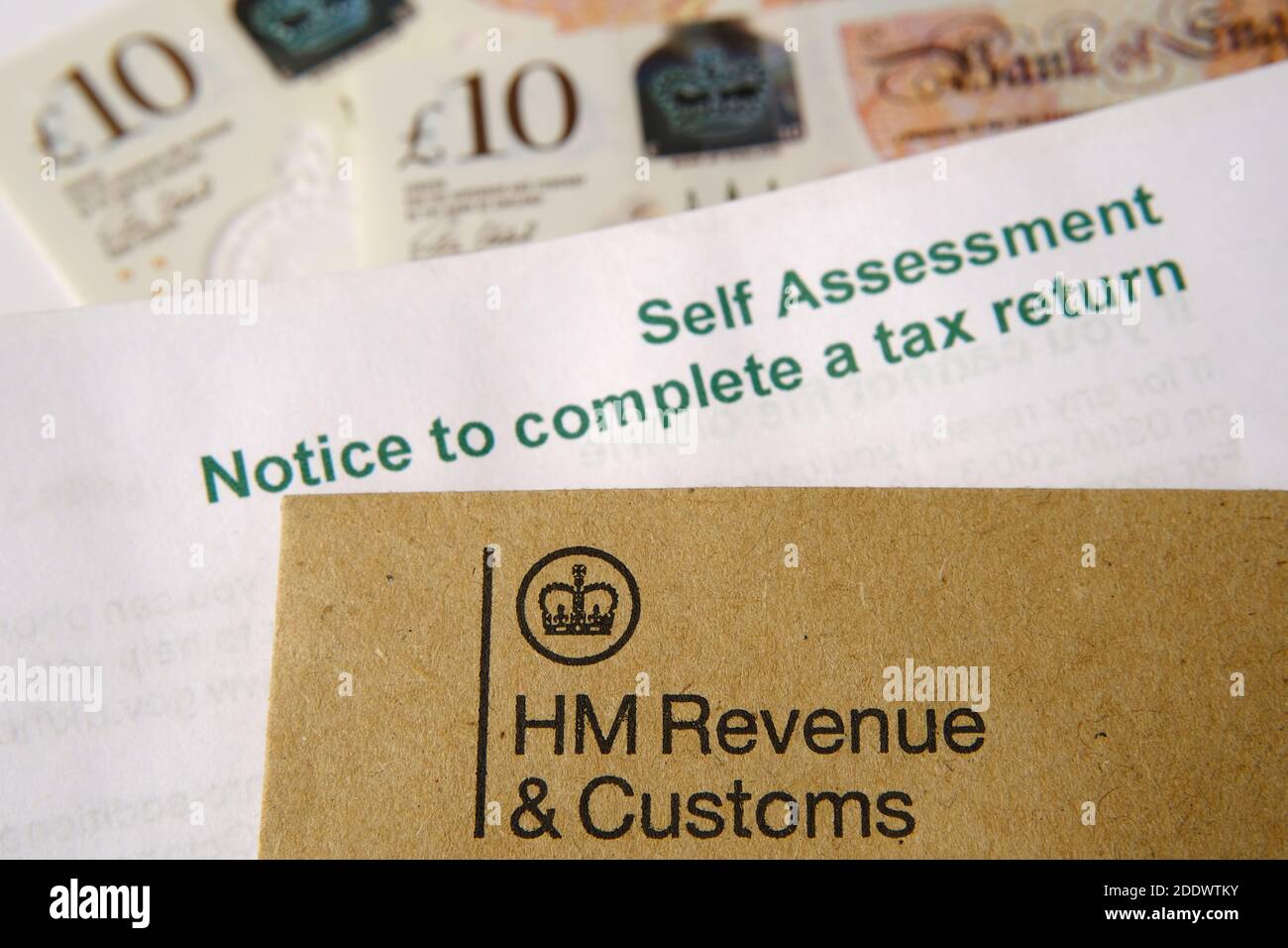 HM Revenue and Customs (HMRC) Buchstaben mit Logos mit dem braunen Umschlag und verschwommenem Selbstbewertungs- und Steuererklärung. Stockfoto
