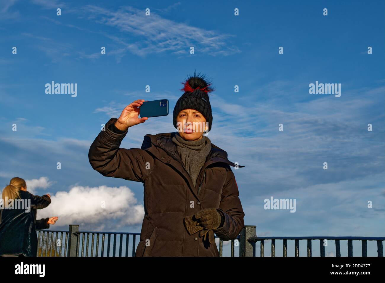 Frau in Beanie nimmt Smartphone Selfie im Herbst Park Stockfoto