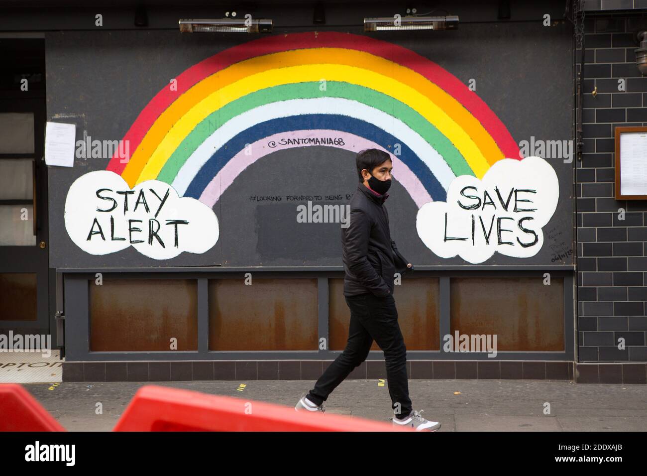 London, Großbritannien. November 2020. Ein Mann geht an einem Aufenthalt vorbei Alarm Leben retten Regenbogen-Schild in Soho während der zweiten Sperre London wird in Tier 2-Beschränkungen gesetzt, wenn Englands nationale Sperre zu Ende geht, da alle nicht wichtigen Geschäfte bis zum 2. Dezember geschlossen sind. Kredit: SOPA Images Limited/Alamy Live Nachrichten Stockfoto