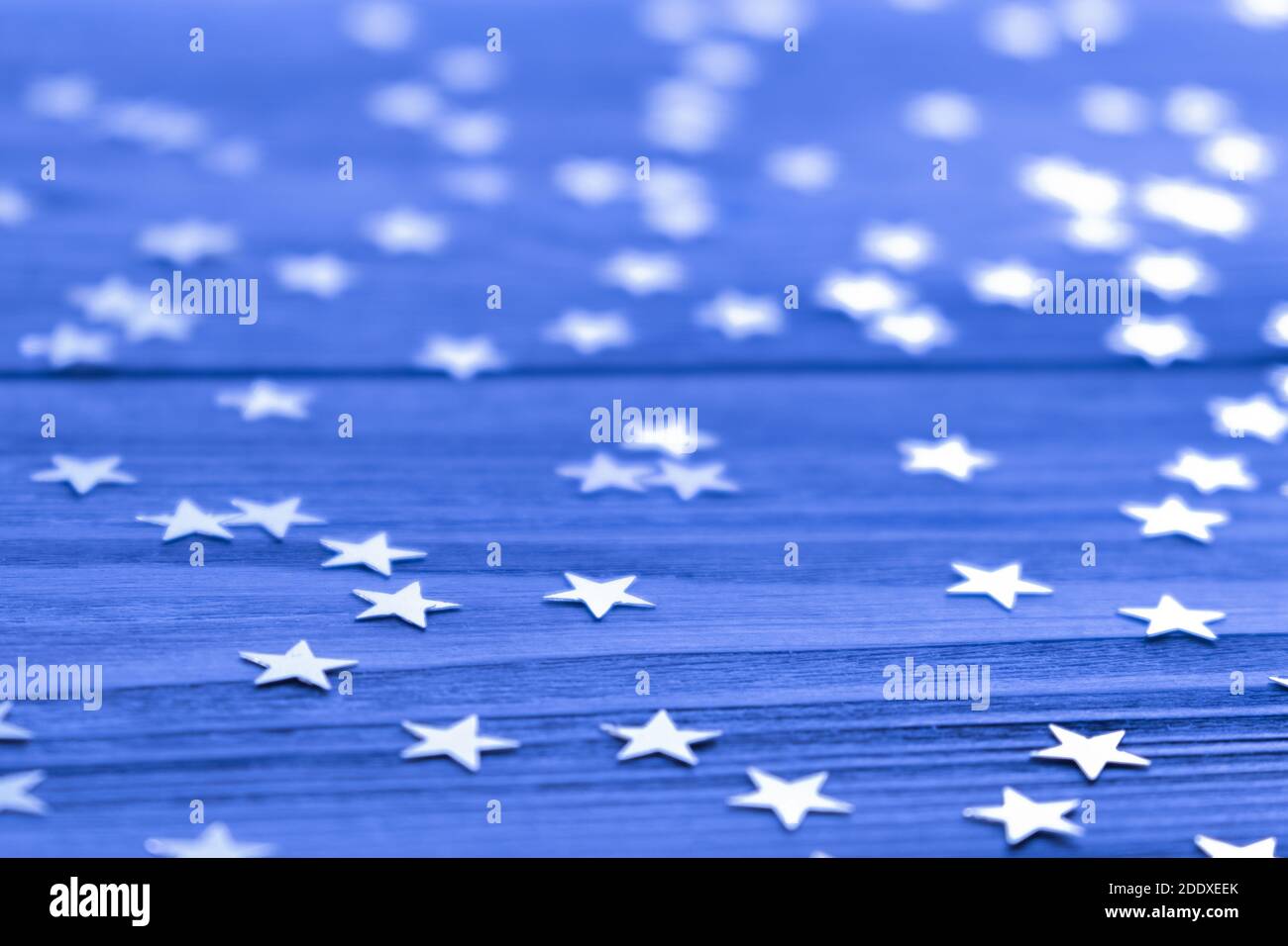 Festlicher kreativer Hintergrund mit funkelnden Konfetti in Form von Sternen auf blauer Kulisse. Urlaubskonzept. Selektiver Fokus. Nahaufnahme. Speicherplatz kopieren. Stockfoto