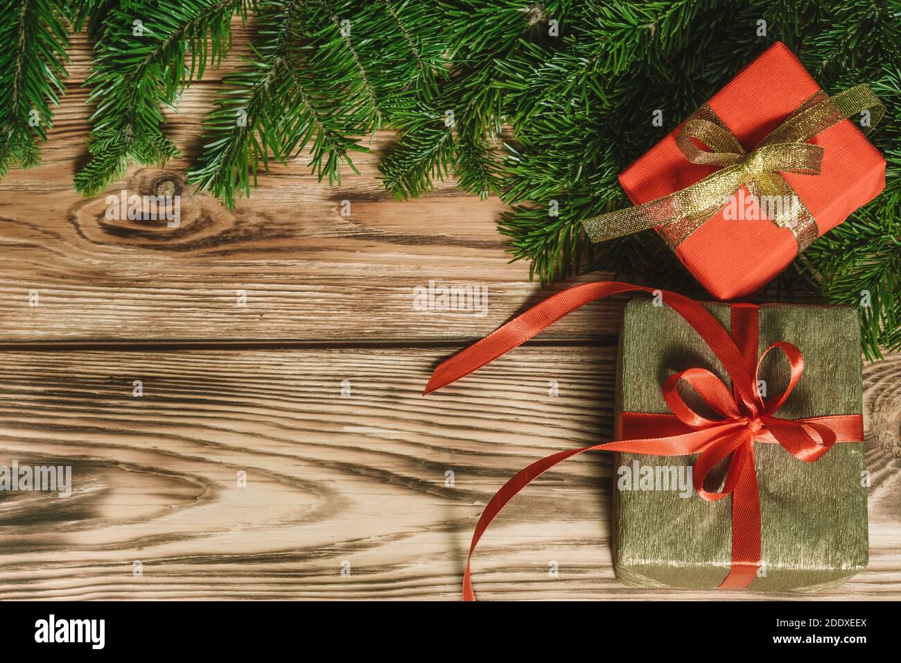 Weihnachtskarte mit Geschenken und Tannenzweigen auf einem Holzhintergrund. Überraschungen und Geschenke für die Neujahrsferien. Blick von oben. Speicherplatz kopieren. Stockfoto