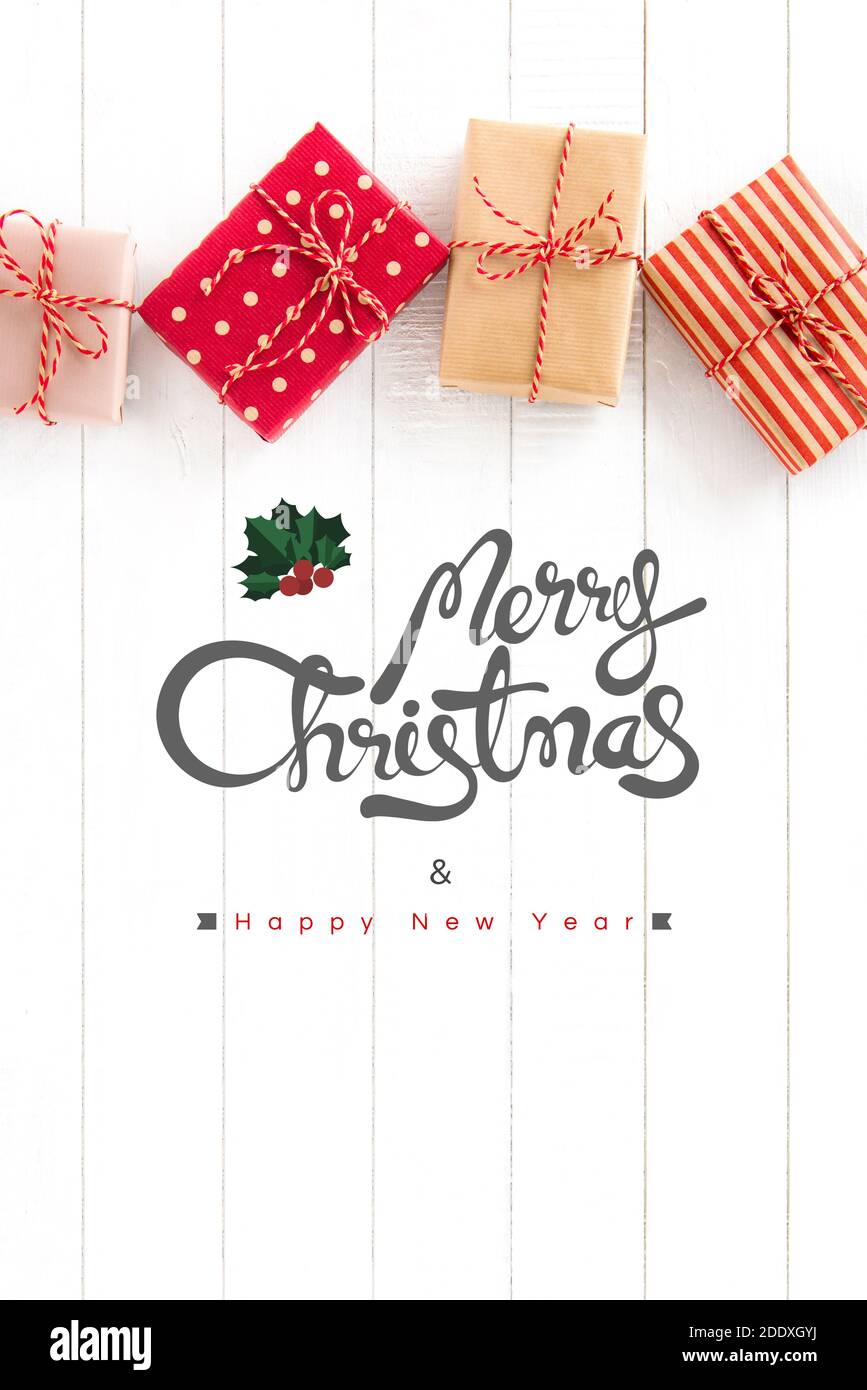 Frohe Weihnachten und glückliches Neues Jahr Text mit Geschenkschachteln auf weißem Holz Hintergrund, Draufsicht Stockfoto