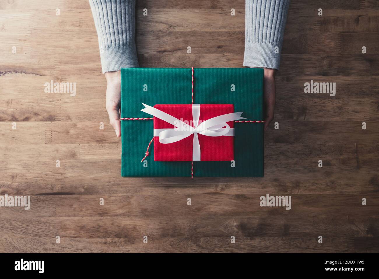 Frau trägt grauen Pullover geben rote und grüne Geschenkboxen für Weihnachtsgeschenk, Draufsicht Stockfoto