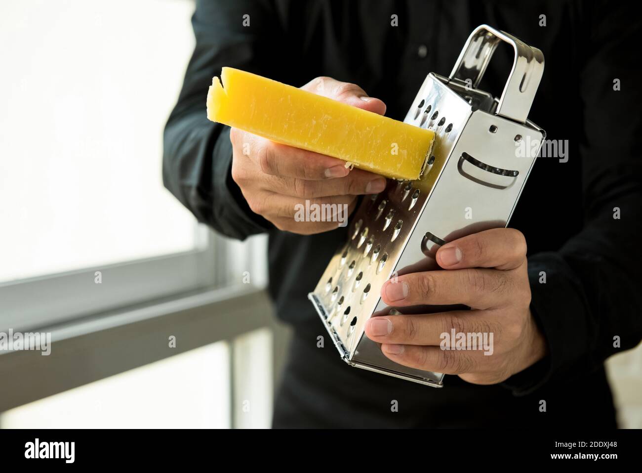 Küchenchef Reibe italienischen Parmesan Käse mit Metallreibe in der Küche Stockfoto