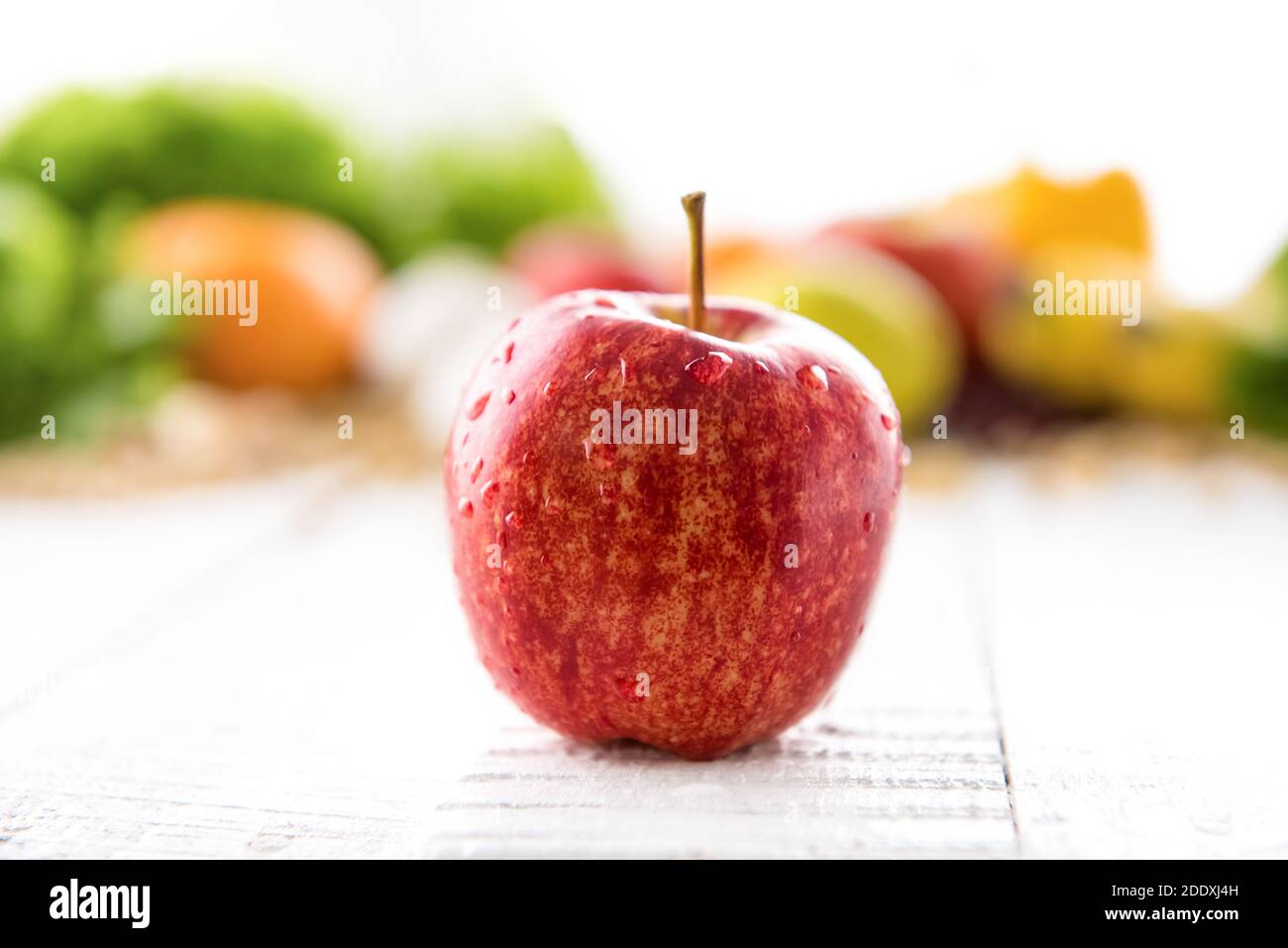 Frischer gesunder roter Gala Apfel auf weißem Holztisch mit Bunt verschwommen fruchtigen Hintergrund Stockfoto