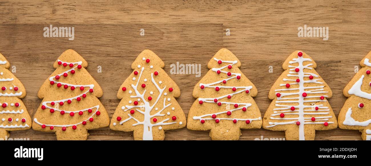 Festlich dekoriert Weihnachtsbaum Form Lebkuchen Cookies in einer Reihe auf Holz Hintergrund, Draufsicht Panorama-Banner Stockfoto