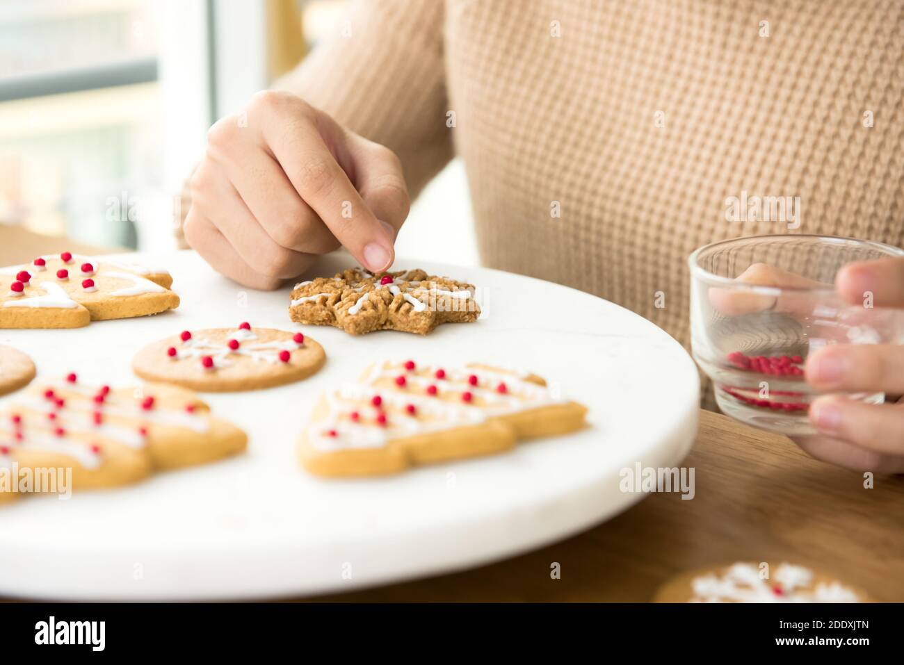 Junge Frau Dekoration hausgemachte Lebkuchen Weihnachtskekse auf weißem Teller In der Küche Stockfoto