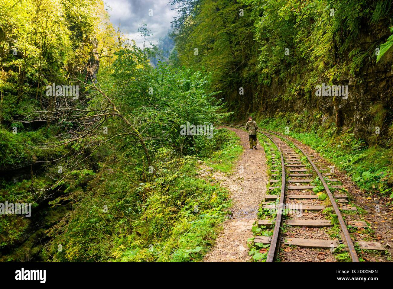 Rückansicht des Touristen in Camouflage genießen erstaunliche Schönheit der Natur. Ausflug auf der alten schmalen Eisenbahn in Bergregion. Stockfoto