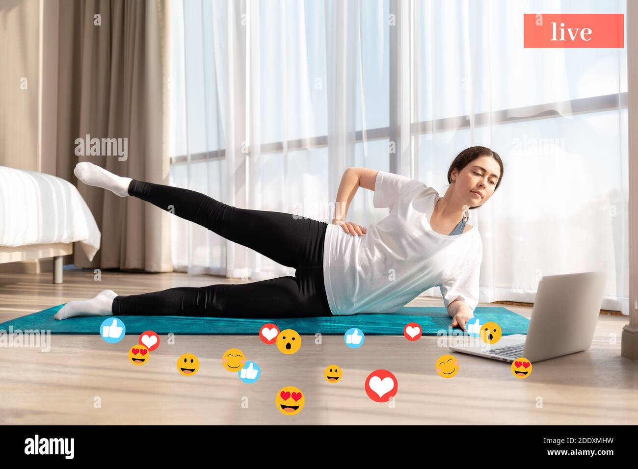 Eine junge Frau macht Yoga live. Seitenansicht. Auf dem Boden befindet sich ein Laptop. Das Konzept des Streamings. Stockfoto