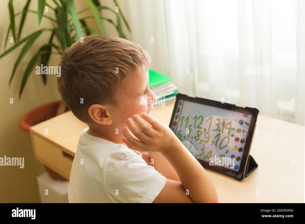 Lächelnder Junge unterrichtet Mathematik auf Tablet zu Hause. Kind mit Gadgets für das Studium der Mathematik. Homeschooling während der Quarantäne Stockfoto