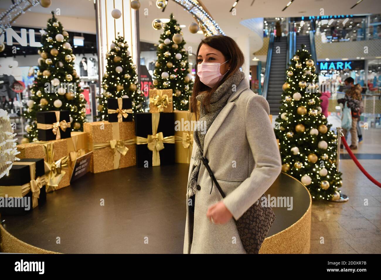 Thema Bild Gefangene in der Coronavirus-Pandemie am 26. November 2020. Eine junge Frau mit Gesichtsmaske, Maske in einer Mall, Einkaufszentrum, sie schaut auf die Weihaftertsverehrung, Weihaftertsbaum, Pandemie, Sperrung, Abschaltung, Inzidenzwert. MODELL FREIGEGEBEN! Weltweite Nutzung Stockfoto
