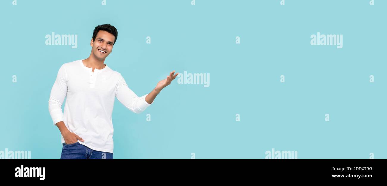 Hübscher junger indischer Mann, der lächelt und seine Hand isoliert geöffnet hat Auf hellblauem Studiohintergrund mit Kopierbereich Stockfoto
