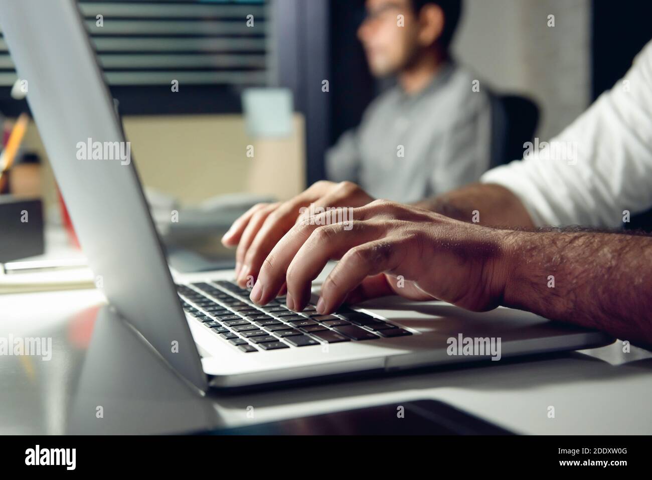 Hände eines Mannes, der auf einem Laptop-Computer tippt, der Überstunden arbeitet Spät in der Nacht im Büro an seinem Schreibtisch Stockfoto