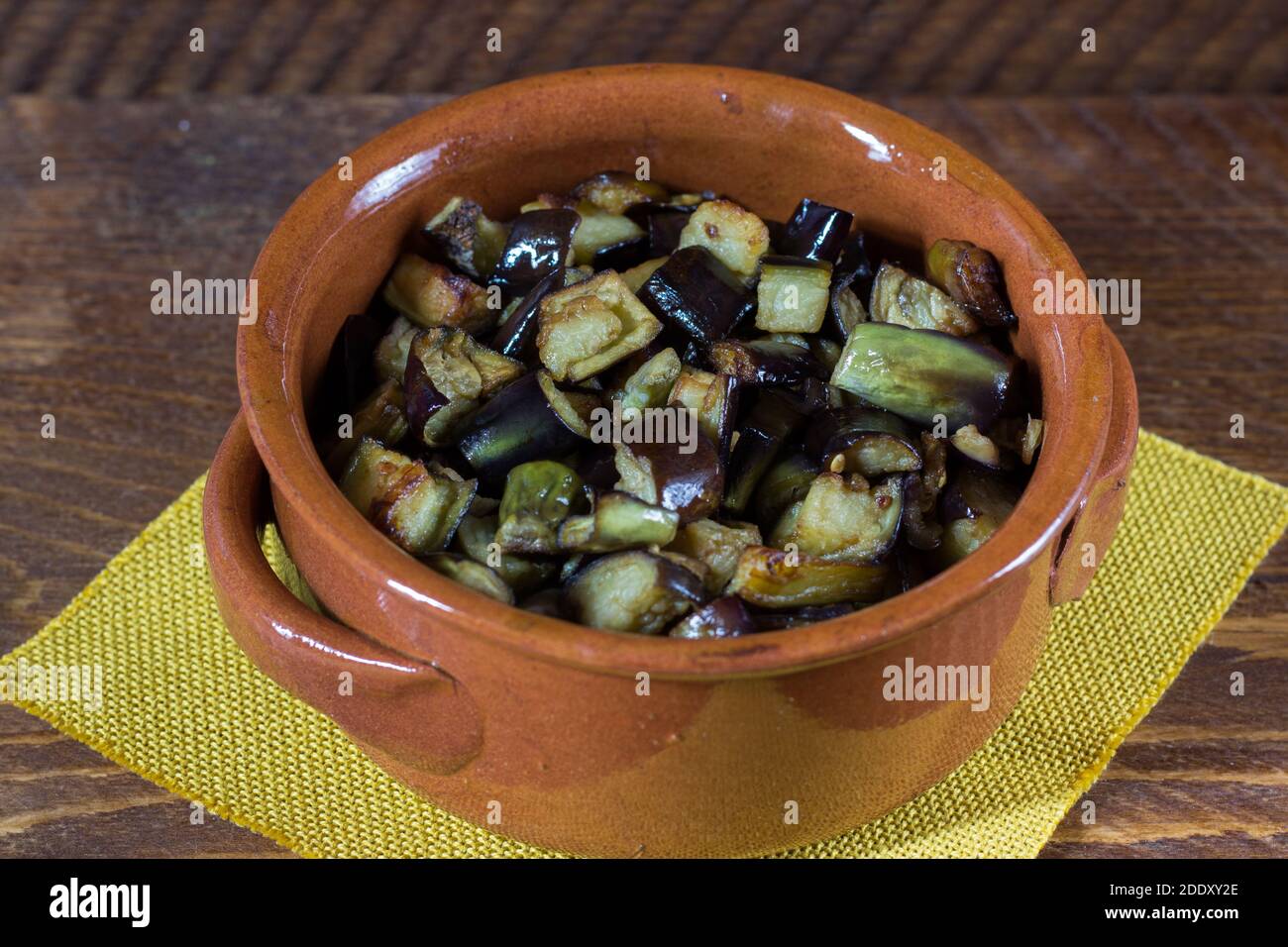 Aubergine in kleiner Pfanne auf Holzhintergrund gewürfelt. Stockfoto