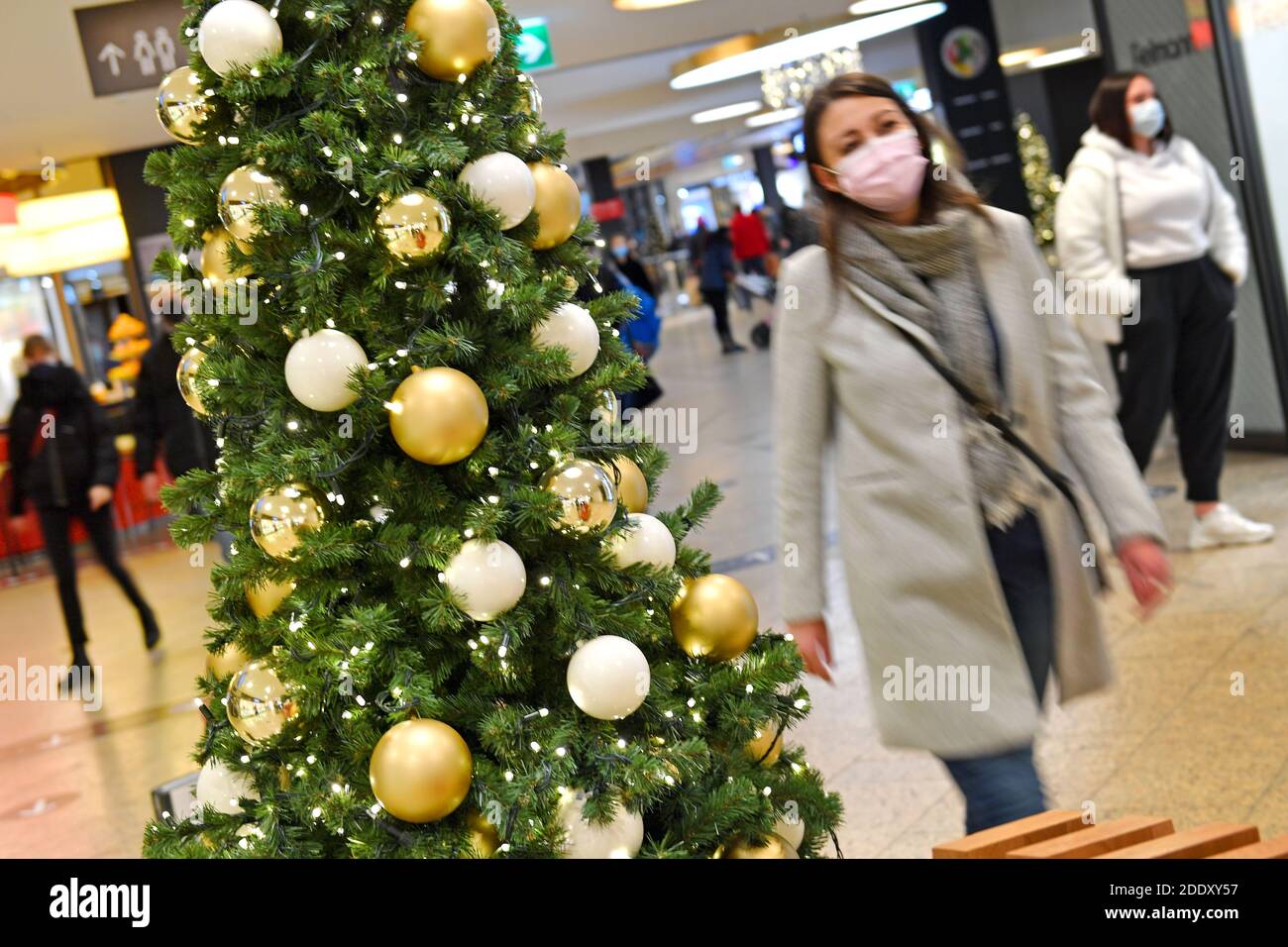 Thema Bild Gefangene in der Coronavirus-Pandemie am 26. November 2020. Eine junge Frau mit Gesichtsmaske, Maske geht in einem Einkaufszentrum an einem Weihaftertsbaum vorbei. Pandemie, Sperrung, Abschaltung, Inzidenzwert. MODELL FREIGEGEBEN! Weltweite Nutzung Stockfoto