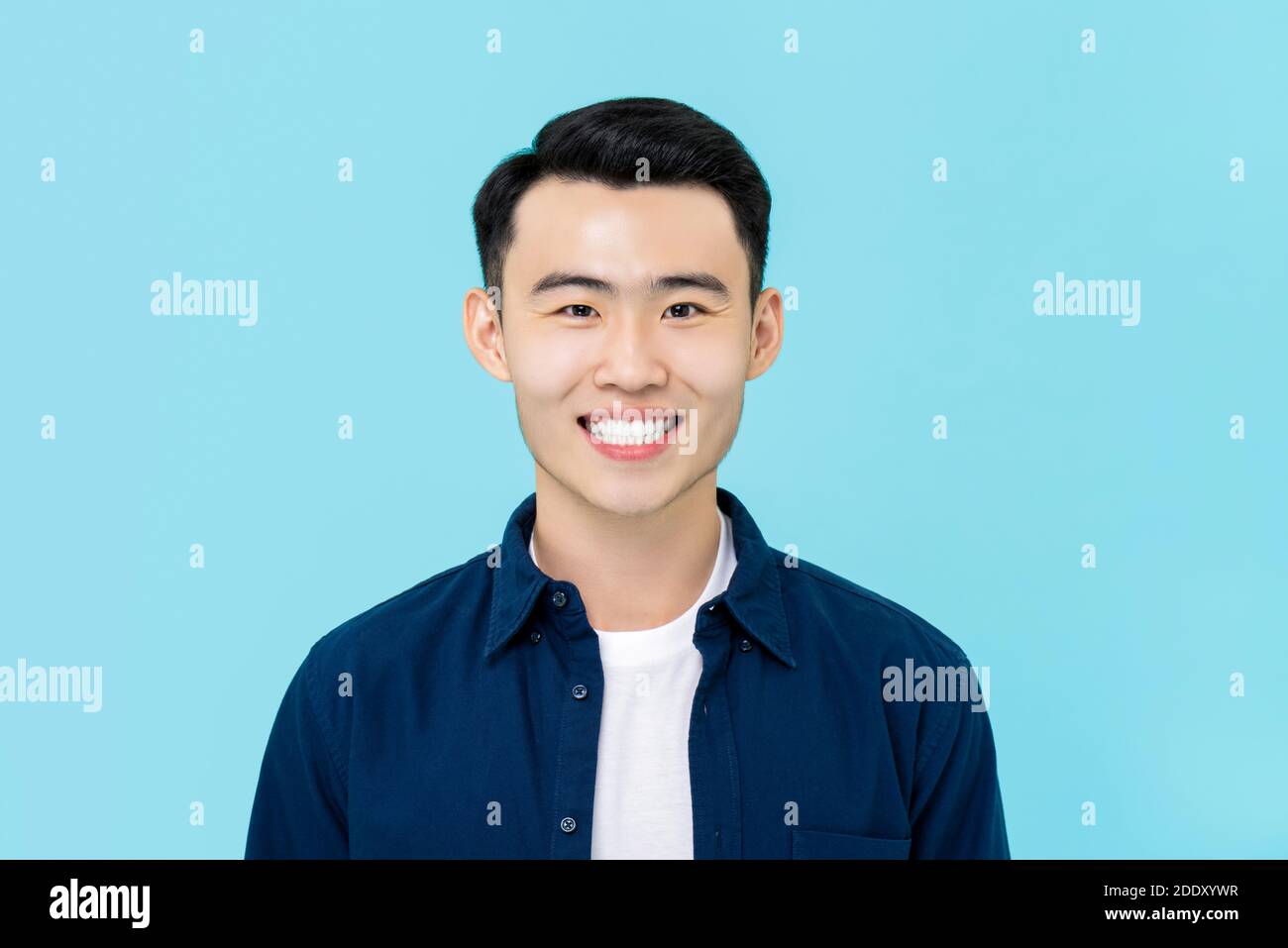 Halbkörper Porträt von lächelnden jungen asiatischen Mann in schlicht Legere Kleidung auf hellblauem Studiohintergrund Stockfoto
