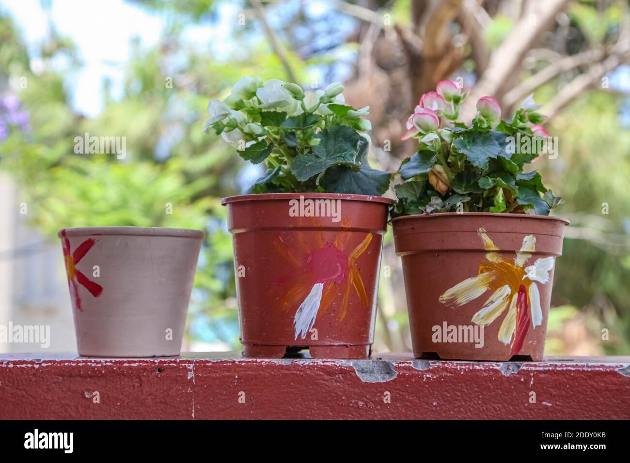 Drei kleine Pflanzentöpfe auf Balkon Kante mit Kindern dekoriert Freihändige Malerei Stockfoto